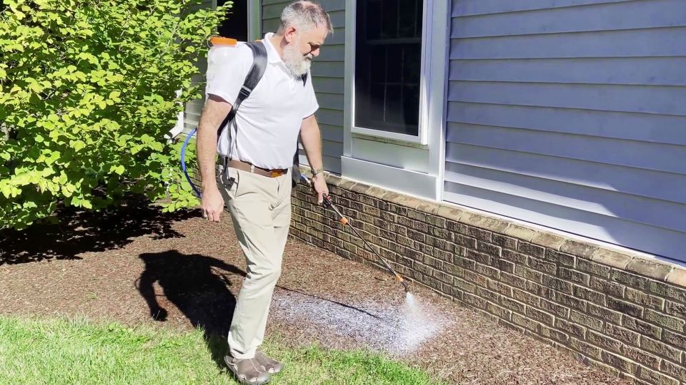 A man spraying mucl glue solution on the mulch